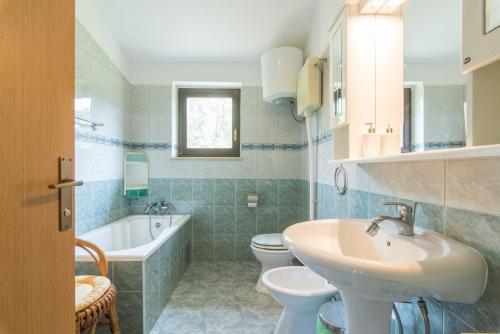 een badkamer met een wastafel, een bad en een toilet bij Apartments Kadum 25 in Poreč