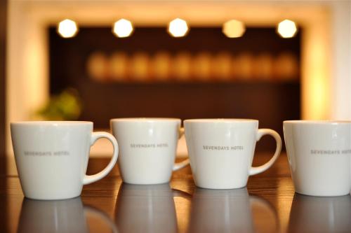 four white coffee mugs sitting on a table at 7 Days Hotel Plus in Kochi
