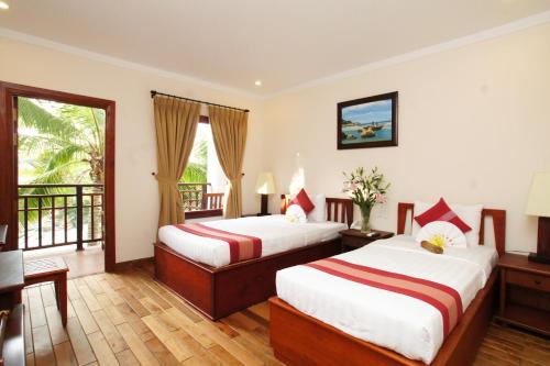 a hotel room with two beds and a balcony at Novela Muine Resort & Spa in Mui Ne