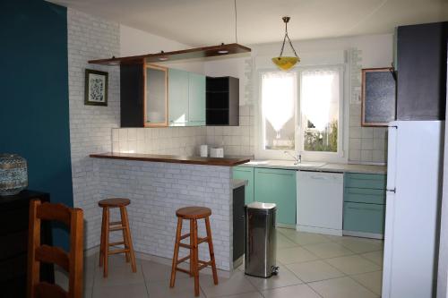 uma cozinha com armários azuis e dois bancos de bar em Gîte La Presqu'île em Bricqueville-sur-Mer