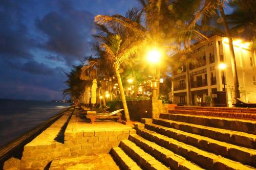 a street with benches and palm trees and a building at Novela Muine Resort & Spa in Mui Ne