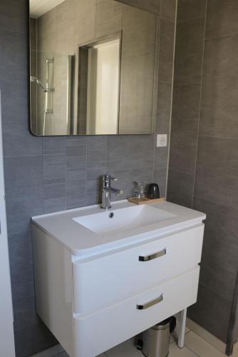 une salle de bain avec un lavabo blanc et un miroir dans l'établissement Gîte La Presqu'île, à Bricqueville-sur-Mer