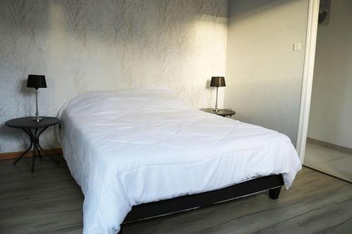 - une chambre avec un lit blanc et 2 tables dans l'établissement Gîte La Presqu'île, à Bricqueville-sur-Mer