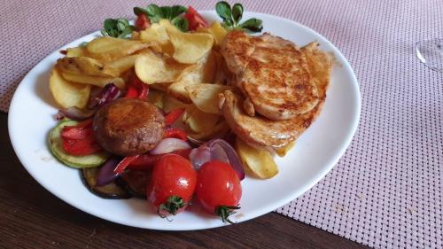 a plate of food with meat and vegetables on a table at PENSIUNE RESTAURANT OVIDIU in Valea lui Mihai