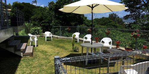 a patio with a table and chairs and an umbrella at SOU東恩納 in Uruma