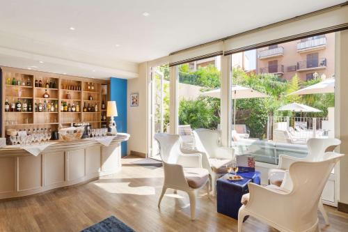 a restaurant with white chairs and a bar with windows at Best Western Hotel Matisse in Sainte-Maxime