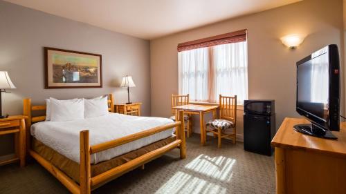 a hotel room with a bed and a flat screen tv at Best Western Plus Plaza Hotel in Thermopolis