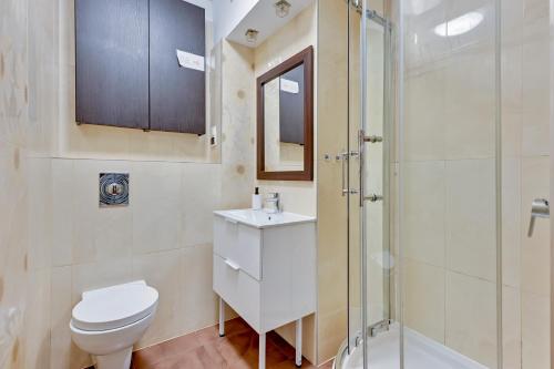 uma casa de banho com um WC e uma cabina de duche em vidro. em Grand Apartments - Apartment for 7 people in Sopot em Sopot