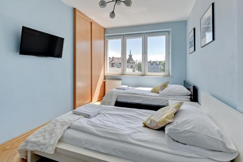 Duas camas num quarto com televisão e janela em Grand Apartments - Apartment for 7 people in Sopot em Sopot