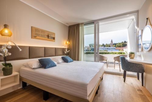 a bedroom with a bed and a desk and a window at Hotel Histrion in Portorož