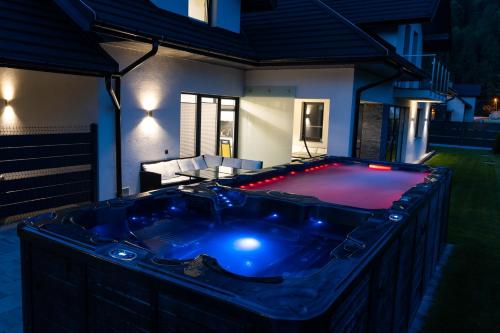 a hot tub in the backyard of a house at night at DOMINO-APARTAMENTY Red in Krościenko