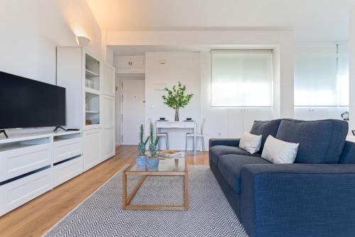 un soggiorno con divano blu e TV di Genteel Home Castilla Terrace a Siviglia