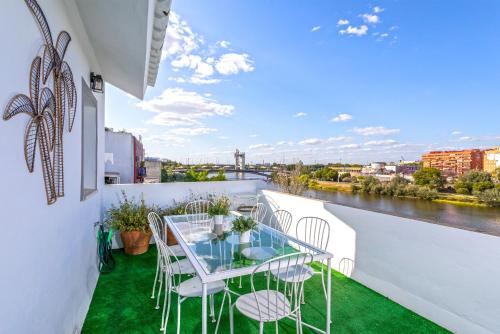 un balcone con tavolo, sedie e un fiume di Genteel Home Castilla Terrace a Siviglia