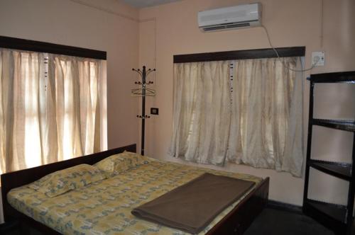 a bedroom with a bed and two windows at Nandanam Homestay in Trivandrum