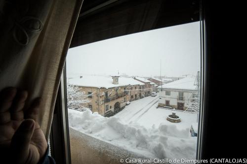 a person looking out a window at a snow covered city at Casa Rural Castillo Diempures in Cantalojas
