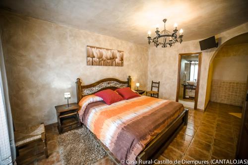 a bedroom with a bed and a chandelier at Casa Rural Castillo Diempures in Cantalojas
