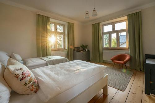- une chambre avec un lit, une chaise et des fenêtres dans l'établissement Vila NMNM, à Nové Město na Moravě