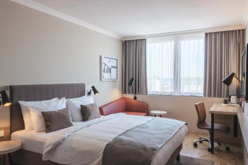 a hotel room with a large bed and a desk at Crowne Plaza Frankfurt Congress Hotel by IHG in Frankfurt/Main