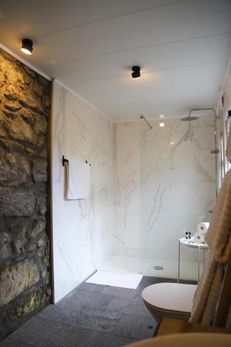 a bathroom with a shower and a stone wall at Sete Cidades Nature Villa in Sete Cidades