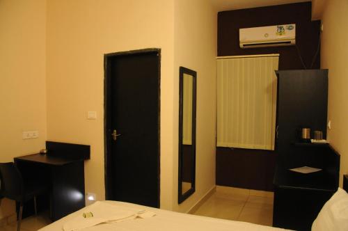 a bedroom with a bed and a mirror and a door at Hotel Sri Krishna Residency in Udupi