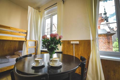 a table with two cups and a vase of flowers at HOSTEL STONEWALL in Poznań