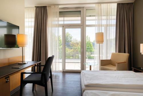 a hotel room with a bed and a desk and a window at Seminaris Hotel Potsdam Griebnitzsee in Potsdam
