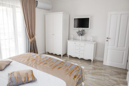 a white bedroom with a bed and a tv at Pensiunea Carpe Diem Spa in Dumbrăviţa