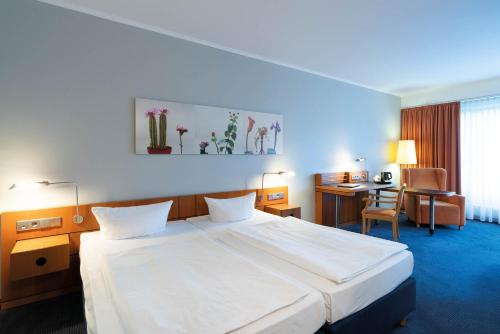 a hotel room with a large bed and a desk at Seminaris Hotel Potsdam Griebnitzsee in Potsdam