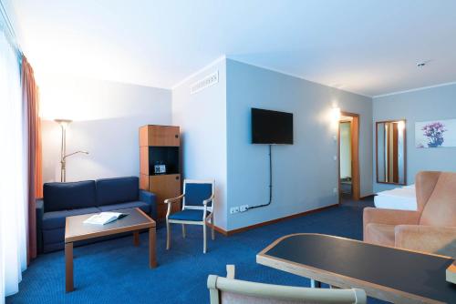 a hotel room with a couch and a tv at Seminaris Hotel Potsdam Griebnitzsee in Potsdam