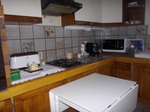 Il comprend une cuisine équipée d'une cuisinière et d'un comptoir blanc. dans l'établissement CHAMBRE CHEZ L'HABITANT NOISIEL, à Noisiel