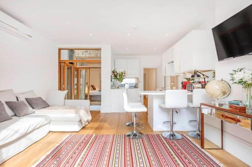 a living room with a white couch and a kitchen at Fulham Broadway 2-Bed Apt w Garden & Pets Ok in London