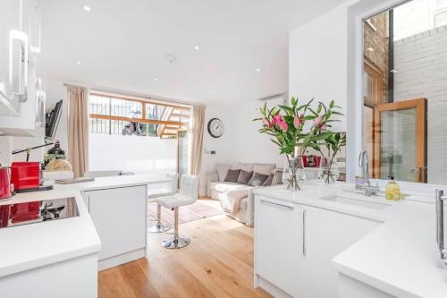 a kitchen with white counters and a living room at 2 bed garden flat with air con by Fulham Broadway in London