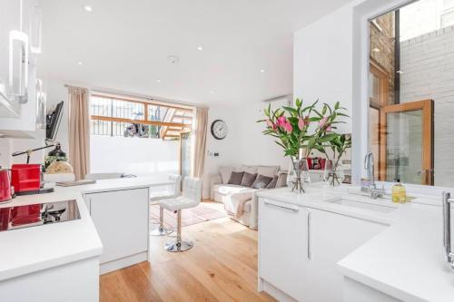 a kitchen with white counters and a living room at 2 Bed - Fulham Broadway - Garden - Pets Allowed in London