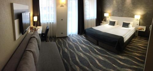 a hotel room with a bed and a couch at Hotel Azur Siofok in Siófok