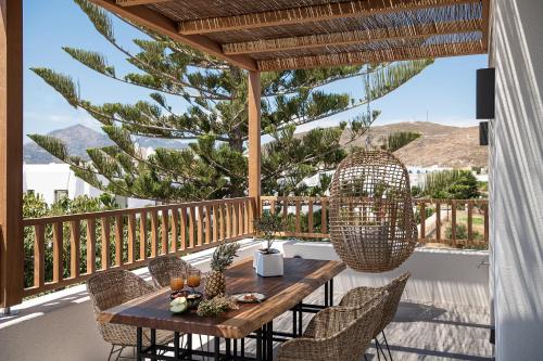 eine Terrasse mit einem Holztisch und Stühlen auf dem Balkon in der Unterkunft Athina Milos Suites in Adamas