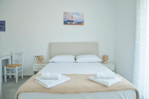 a white bedroom with a bed with two towels on it at Zeras Apartments in Adamas