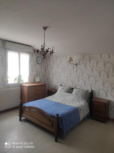 ein Schlafzimmer mit einem Bett mit einer blauen Decke in der Unterkunft POIRSON THIERY in Hagécourt