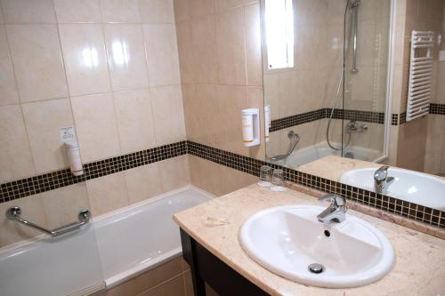 a bathroom with a sink and a bath tub at Hotel Azur Siofok in Siófok