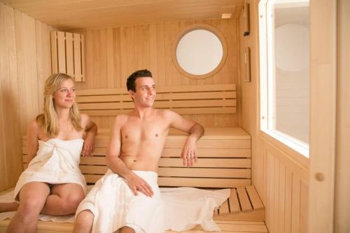 a man and woman sitting in a sauna at Ferienwohnung Schlossblick in Güstrow