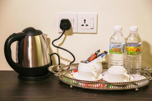 a tea kettle and a tray with cups and water bottles at K Garden Hotel Parit Buntar in Parit Buntar