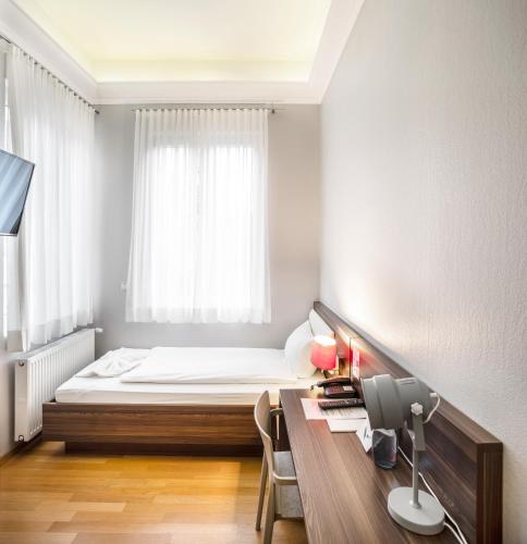 a bedroom with a bed and a desk with a computer at BoardingWorld Heidelberg in Heidelberg