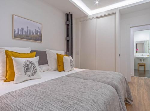 ein Schlafzimmer mit einem großen Bett mit gelben und weißen Kissen in der Unterkunft Semisótano cercano al Retiro Lagasca Retiro II in Madrid