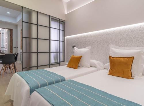 2 camas en una habitación de hotel con almohadas amarillas y azules en ESPOZ Y MINA II en Madrid