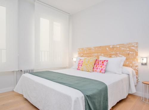 a bedroom with a large white bed with colorful pillows at CASTELLO IV in Madrid