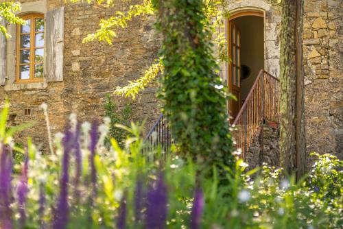 a stone house with a staircase and flowers in front of it at Maison d'Hôtes Mas de la Chadenede in Lagorce