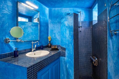 a blue bathroom with a sink and a mirror at Epic View Suites in Akrotiri