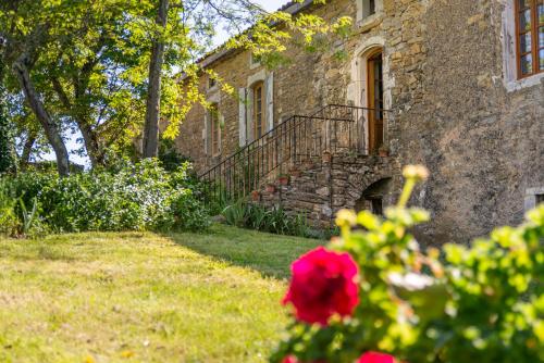 a stone house with a staircase and a red flower at Maison d'Hôtes Mas de la Chadenede in Lagorce