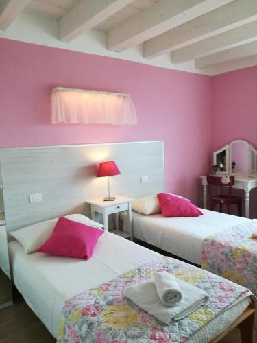 a room with two beds with pink walls at B&B Aria d'Argento & Relax Home in Trento