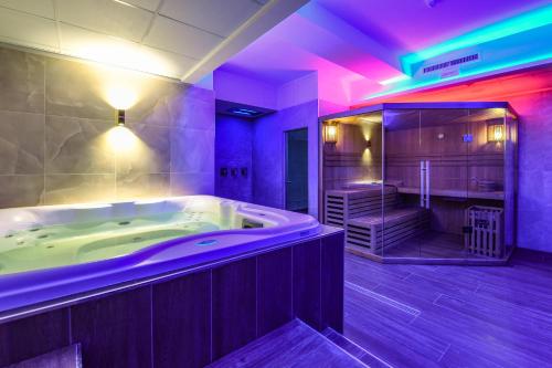 un ampio bagno con vasca e illuminazione viola di Hotel Rivus a Peschiera del Garda