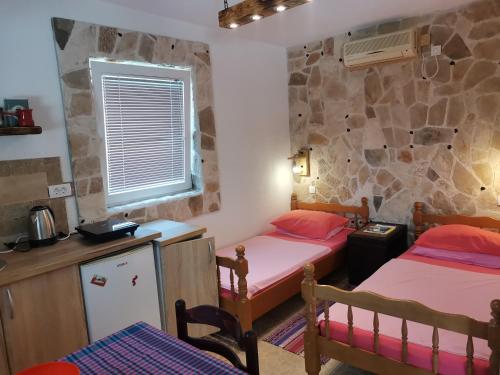 a bedroom with two beds and a stone wall at Apartments Lazarević Sutomore in Sutomore